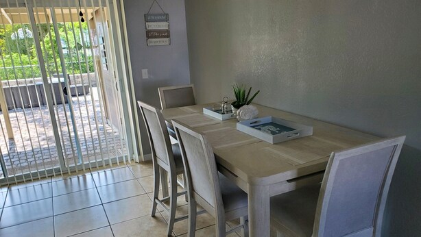 Un comedor con una mesa, sillas, una planta en maceta y un cartel en la pared.