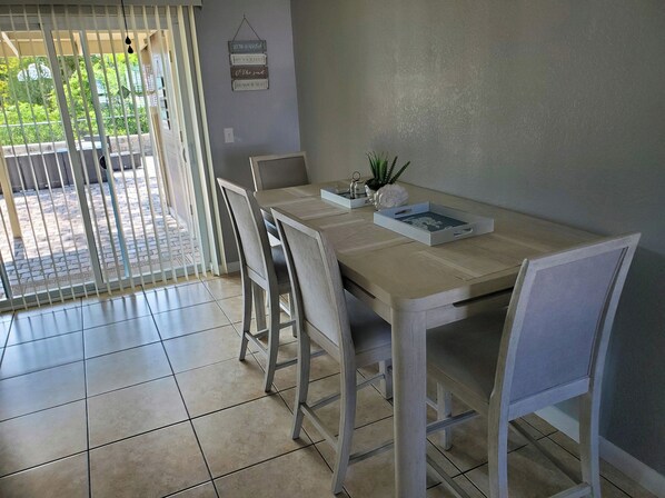 Un comedor con una mesa, sillas, una planta en maceta y un cartel en la pared.