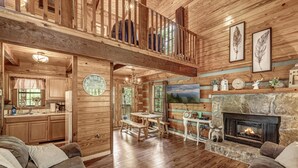 Un salon spacieux doté d’une cheminée, de parquets en bois et d’un coin repas.