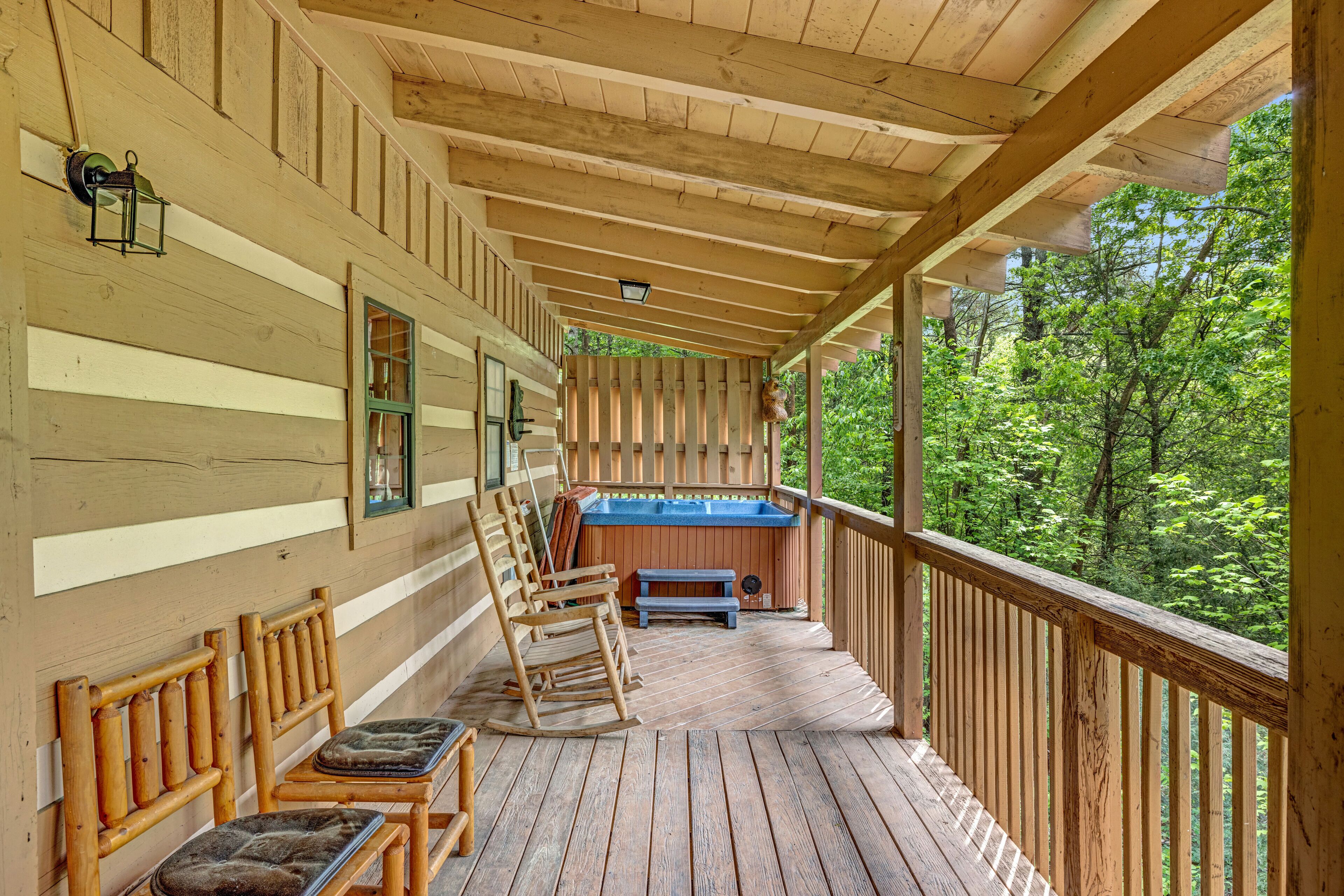 A wooden deck with rocking chairs and a hot tub.