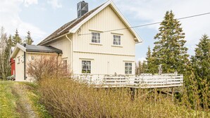 A two-story house with a gabled roof and a chimney, surrounded by trees and a wooden dock. - Amazing home in Ytterøy with WiFi (Ytterøy)
