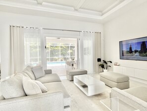 Ein modernes Wohnzimmer mit einer Couch, einem Hocker, einem Couchtisch und einem Bild an der Wand.