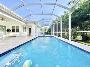 Ein überdachter Pool mit freiem Blick auf die umliegende Bepflanzung und einem hellen Innenraum.