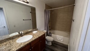 Une salle de bain avec un meuble-lavabo à deux vasques, des toilettes et une baignoire.