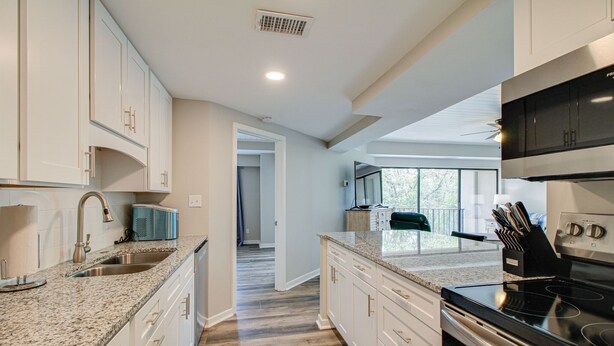A modern kitchen with granite countertops, stainless steel appliances, and white cabinetry. - Newly Renovated 2BR/2BA Flat/3 Smart TV’s/WIFI/Pool & Tennis/Pickleball Views (Hilton Head Island)