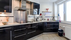 Una cocina moderna con gabinetes negros, electrodomésticos de acero inoxidable y salpicadero de azulejos blancos.