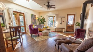 A cozy living room with wooden flooring, a ceiling fan, a sofa, a chair, a coffee table, and a fireplace. - Entire Home in Downtown Eugene (Eugene)