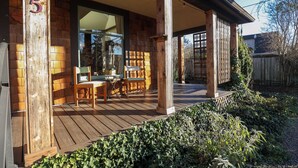 A wooden deck with a table and chairs, a large window, and a wooden fence in the background. - Entire Home in Downtown Eugene (Eugene)