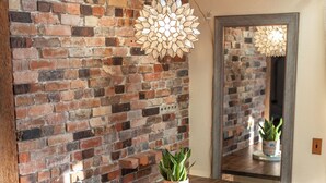 A dining area with a brick wall, wooden table, bench, and chairs. - Entire Home in Downtown Eugene (Eugene)
