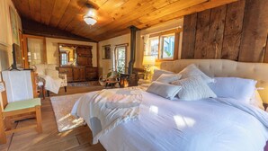 A cozy bedroom with a large bed, wooden ceiling, and a rustic wall. - Entire Home in Downtown Eugene (Eugene)