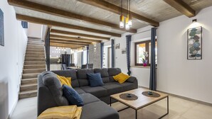 Een moderne woonkamer met een hoekbank, een salontafel en een trap naar een andere kamer.