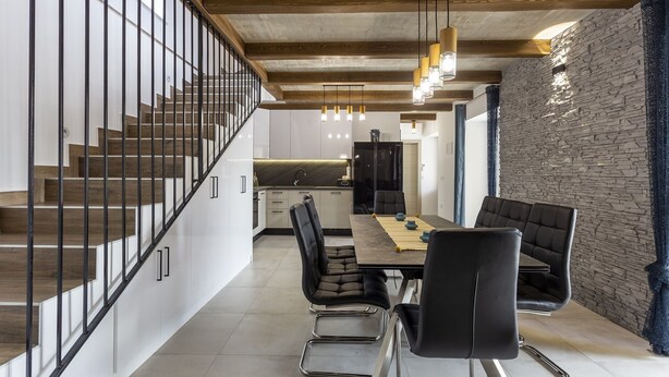 Een modern interieur met een trap, een eethoek, een keuken en een stenen muur.