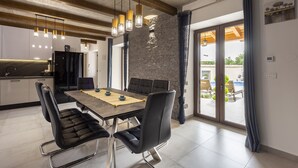 Een moderne eethoek met een houten tafel, zwarte bekleden stoelen en hanglampen.