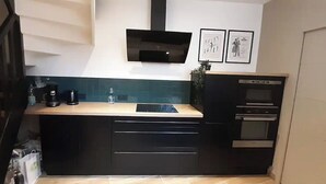 A modern kitchen with a black countertop, built-in oven, and a microwave. - La Petite Bélérit, town house - Landerneau (Landerneau)