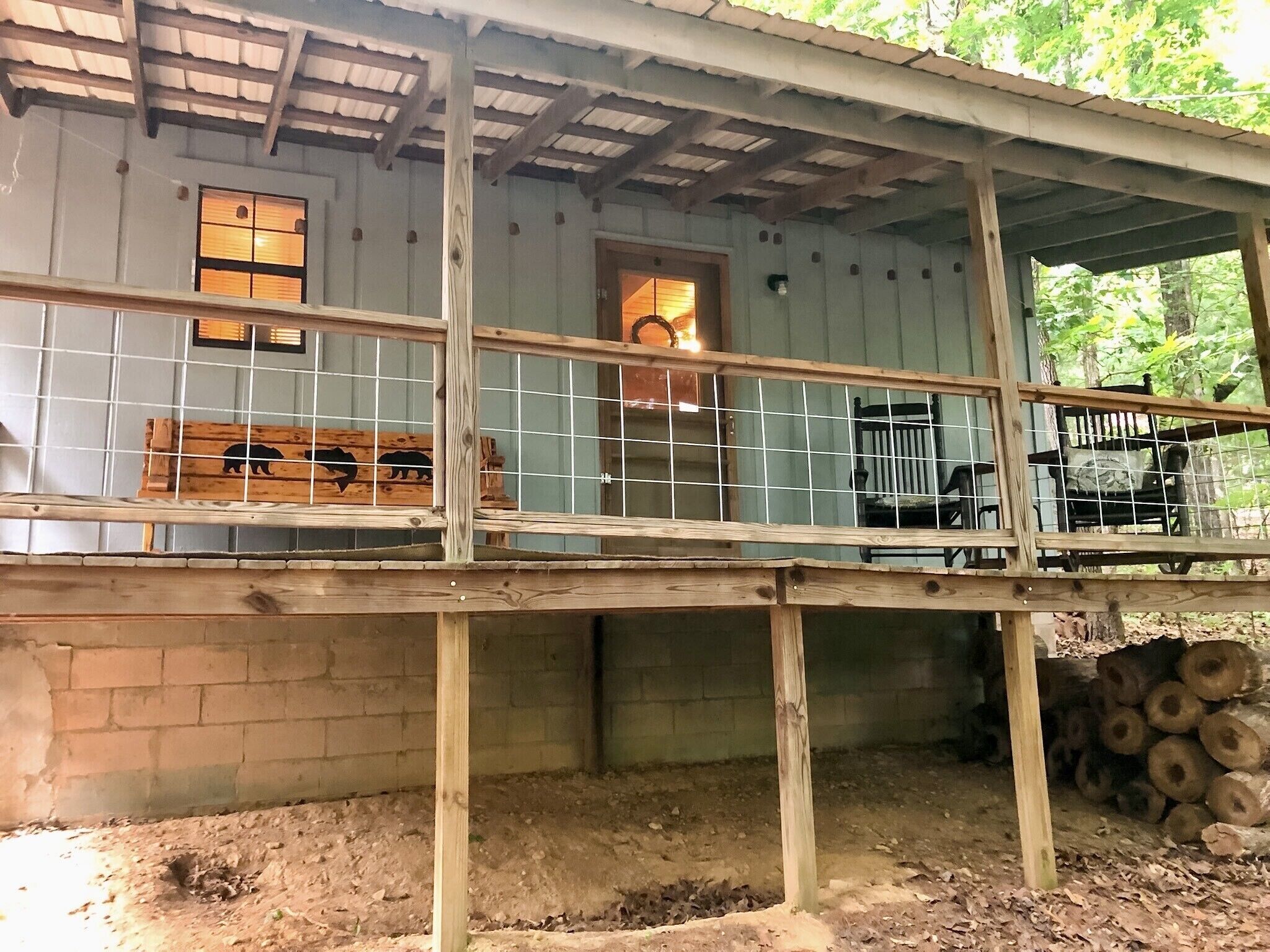 A rustic cabin with a wooden deck, a metal railing, and a small porch area.