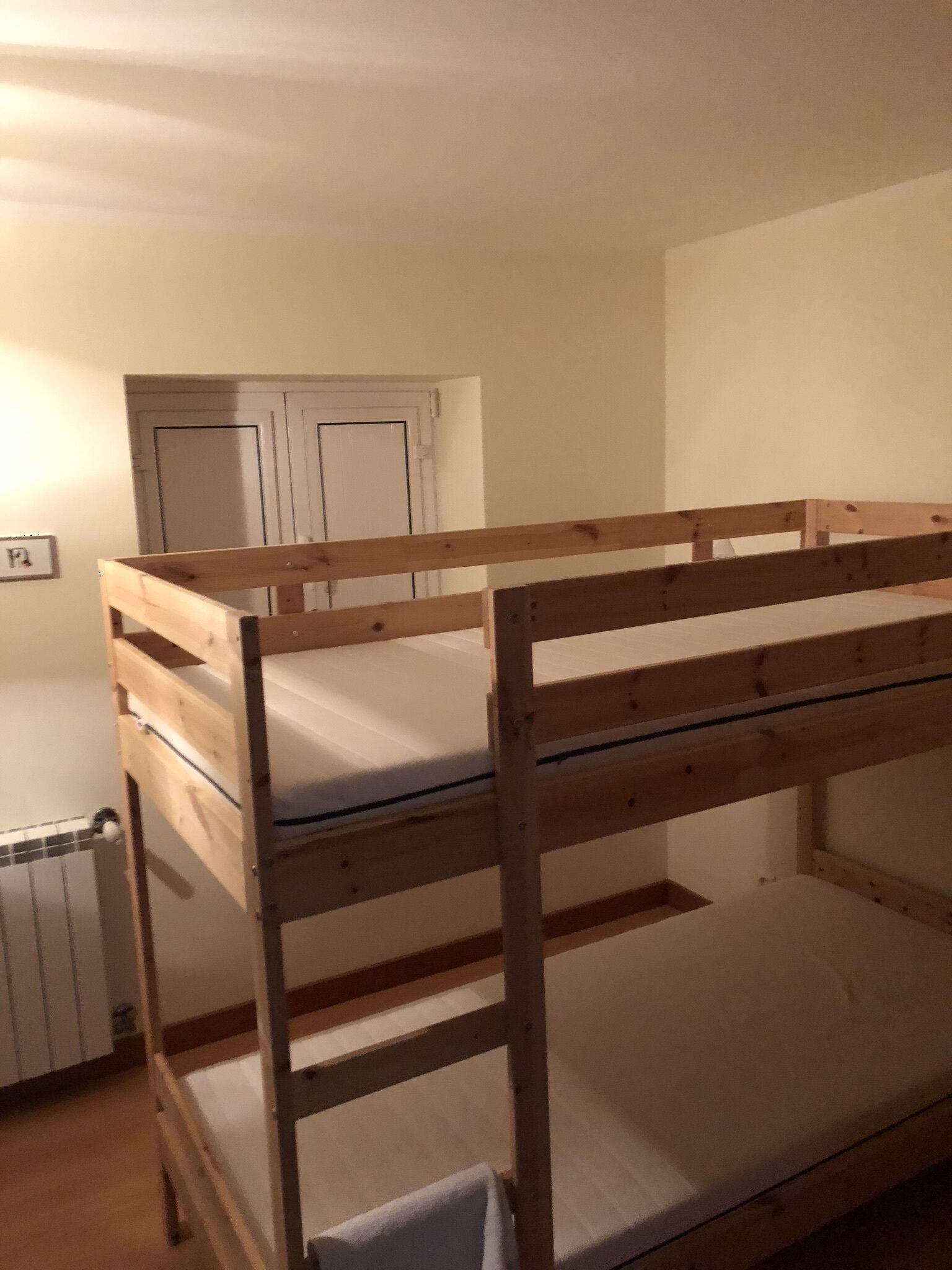Ein Etagenbett in einem Zimmer mit einer weißen Tür und einem Heizkörper.