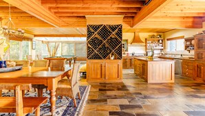 Una cocina amplia con armarios de madera, una vinoteca y un comedor con una mesa grande y sillas.