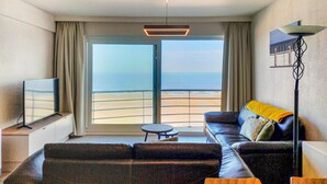 A modern living room with a large window offering a view of the beach.