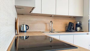 A modern kitchen with a sleek black countertop, stainless steel sink, and a coffee machine.