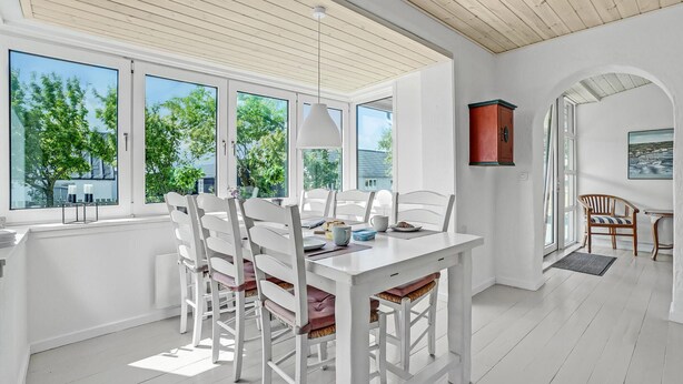 A bright dining area with white furniture, large windows, and a view of greenery outside. - Gorgeous home in Vestervig with WiFi (Vestervig)