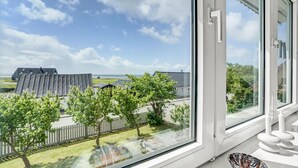 A room with a large window overlooking a residential area, a white door, and a small table with candles. - Gorgeous home in Vestervig with WiFi (Vestervig)