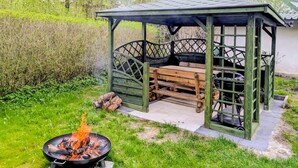 Un kiosque en bois avec un banc, un foyer et un vélo.