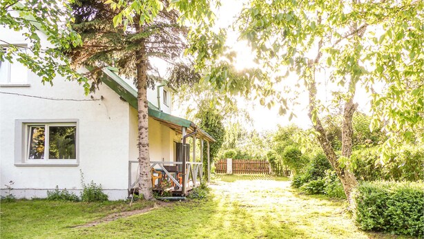Une maison avec un toit végétalisé, une fenêtre bien visible et un chemin menant à une clôture en bois.