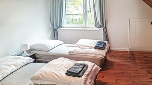 Une chambre avec deux lits, une table de chevet avec une lampe et une fenêtre avec des rideaux.