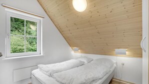 A bedroom with a sloped ceiling, a large window, and a bed with white bedding. - Gorgeous home in Gråsten with sauna (Gråsten)