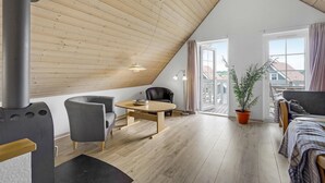 A modern loft bedroom with a sloped ceiling, wooden flooring, a large window, a potted plant, and a cozy seating area. - Gorgeous home in Gråsten with sauna (Gråsten)