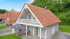 A two-story house with a red-tiled roof, a balcony with white railings, and a patio with outdoor furniture. - Gorgeous home in Gråsten with sauna (Gråsten)