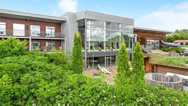A modern building with large glass windows, a wooden facade, and a rooftop garden with seating. - Gorgeous home in Gråsten with sauna (Gråsten)