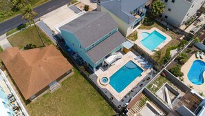 A residential area with a large house featuring a swimming pool, a smaller pool, and a hot tub.