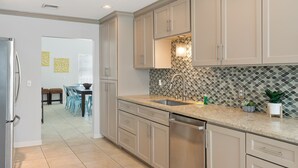 A modern kitchen with beige cabinets, a granite countertop, and a stainless steel dishwasher.