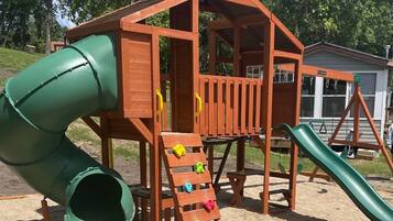 A wooden play structure with a slide and climbing steps.