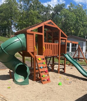 A wooden play structure with a slide and climbing steps. - Charming 2-Bedroom Lakeside Cabin with Dock Access (Alexandria)