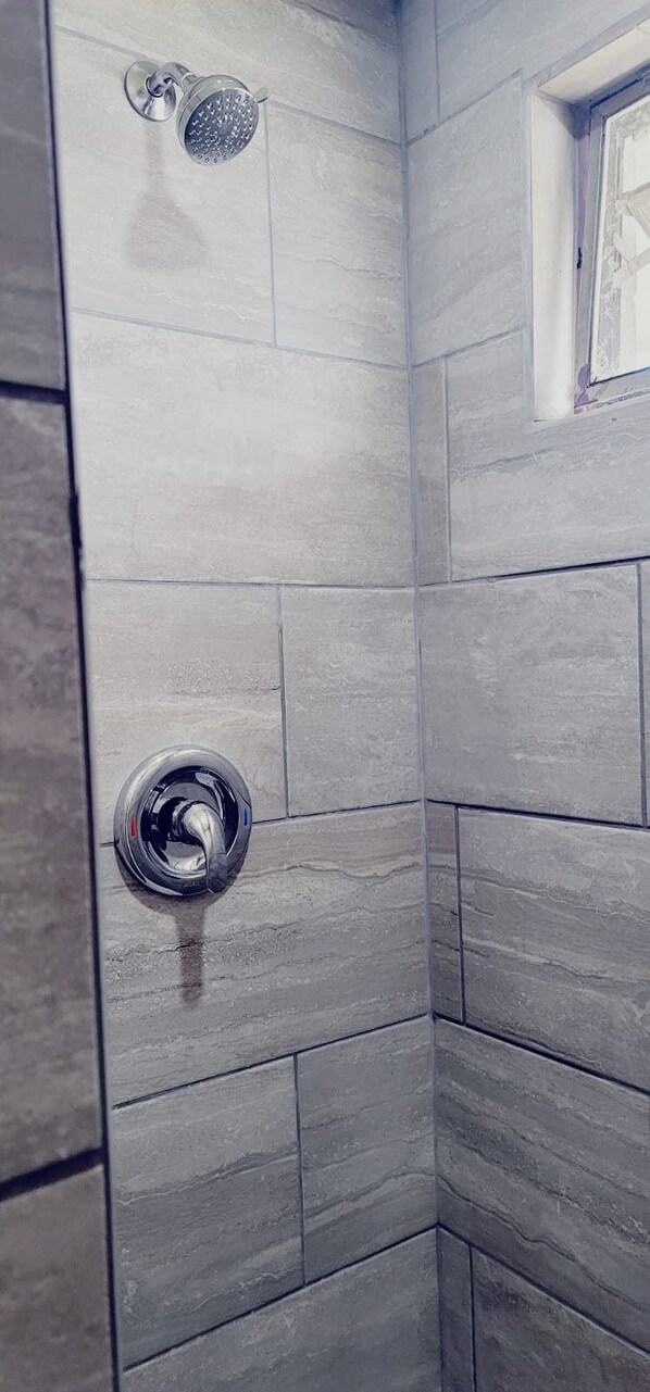 Ein Duschbereich mit Handbrause und am Wand befestigtem Wasserhahn.