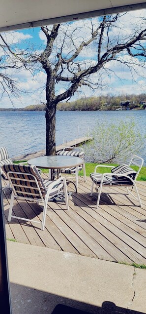 A deck with a table and chairs overlooking a body of water. - Charming 2-Bedroom Lakeside Cabin with Dock Access (Alexandria)