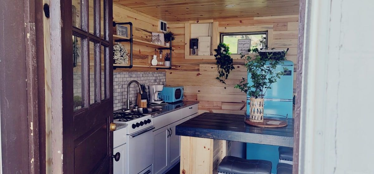 A compact kitchen with a stove, microwave, and sink.