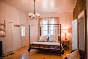 A four-poster bed with a patterned bedspread, a chandelier, and a bedside table with a lamp. - New! Large Victorian home! Outdoor space for entertaining! (Sevierville)