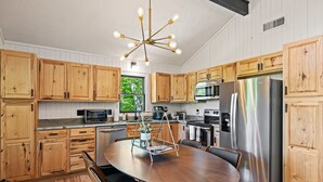 A modern kitchen with wooden cabinets, stainless steel appliances, and a round dining table.