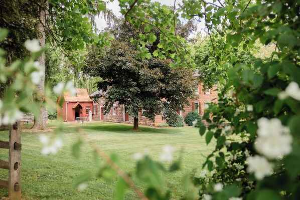 A brick building with a red roof, surrounded by a well-maintained lawn and trees.
