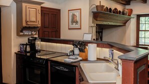 Una cocina rústica con vigas de madera, una cafetera, un lavavajillas y un fregadero.