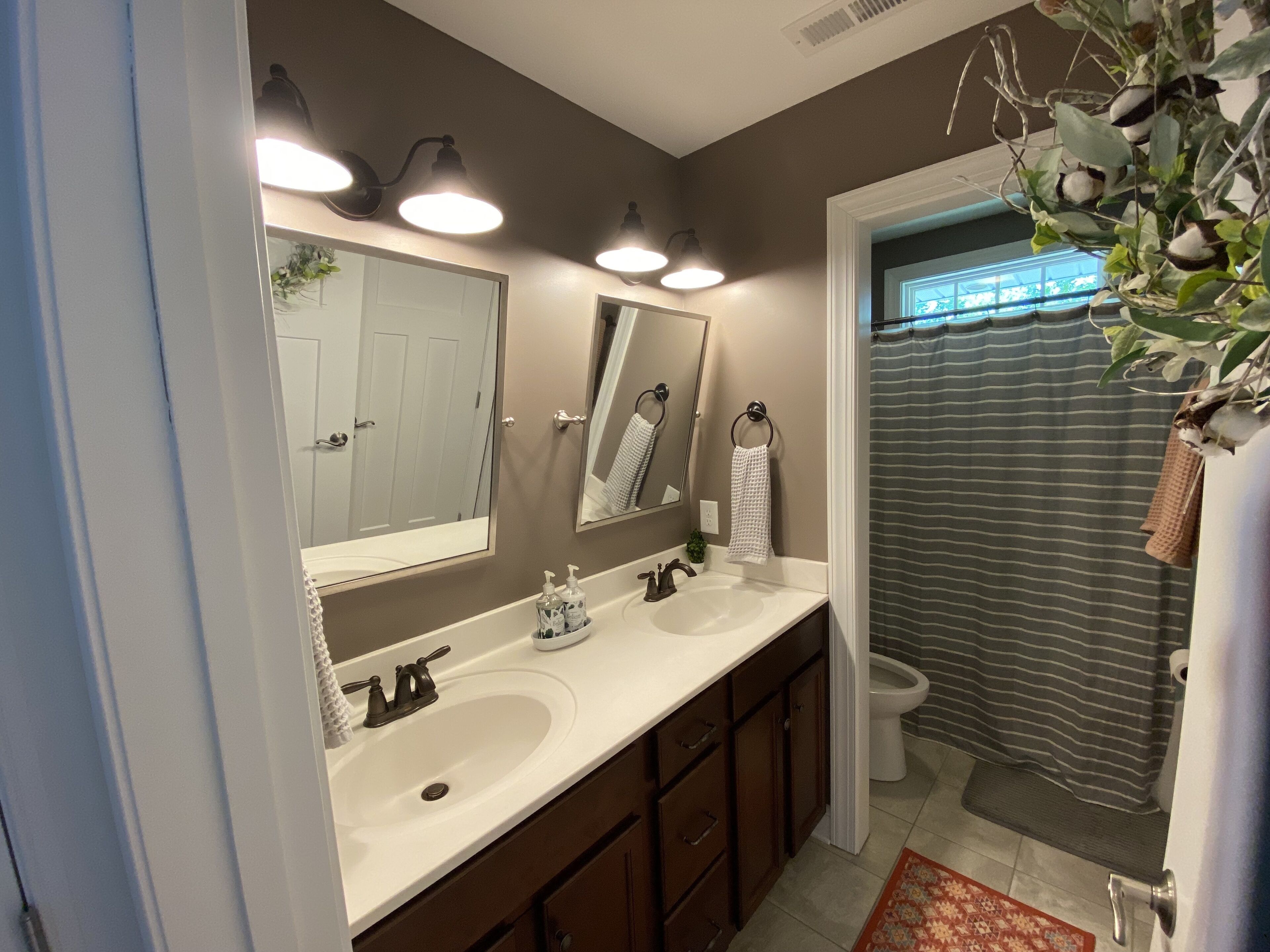 A bathroom with two sinks, a large mirror, and a shower curtain.
