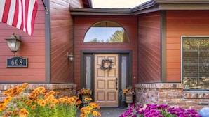 Une maison avec une façade en bois, une porte d’entrée ornée d’une guirlande et une plaque portant le numéro « 608 ».