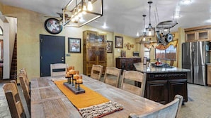 Une cuisine spacieuse avec un grand îlot central, des chaises en bois et une table à manger pour six personnes.
