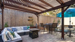 Une terrasse extérieure dotée d’un espace salon couvert, d’une table et de chaises.