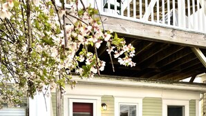Une maison avec une porte rouge, un porche doté d’un canapé en osier et une terrasse en bois.