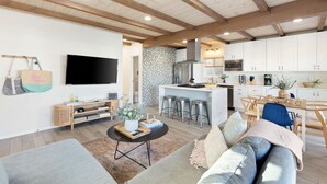 Una cocina moderna con armarios blancos, microondas y refrigerador de acero inoxidable.