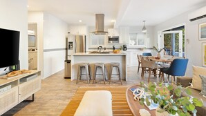 Eine moderne Küche mit einer zentralen Kochinsel, Barhocker und einem Essbereich mit Tisch und Stühlen.